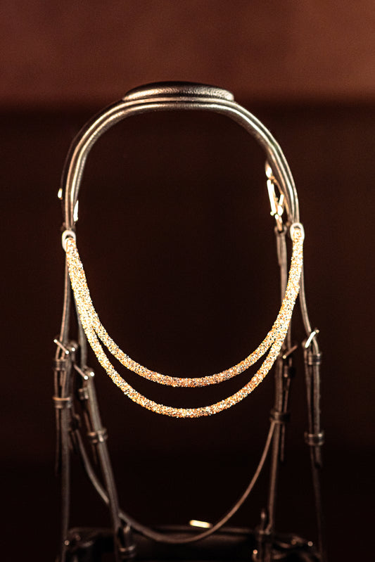 Experience a new dimension of browband design. Crafted with three soft, flexible tubes, each generously sprinkled with dazzling rhinestones, this piece offers a unique texture and radiant sparkle. An internal metal wire allows for effortless shaping, ensuring a perfect contour to your horse's brow and maintaining its elegant form.
Each browband is handmade from scratch using premium European materials and durable leather. Featuring our exclusive magnetic snap