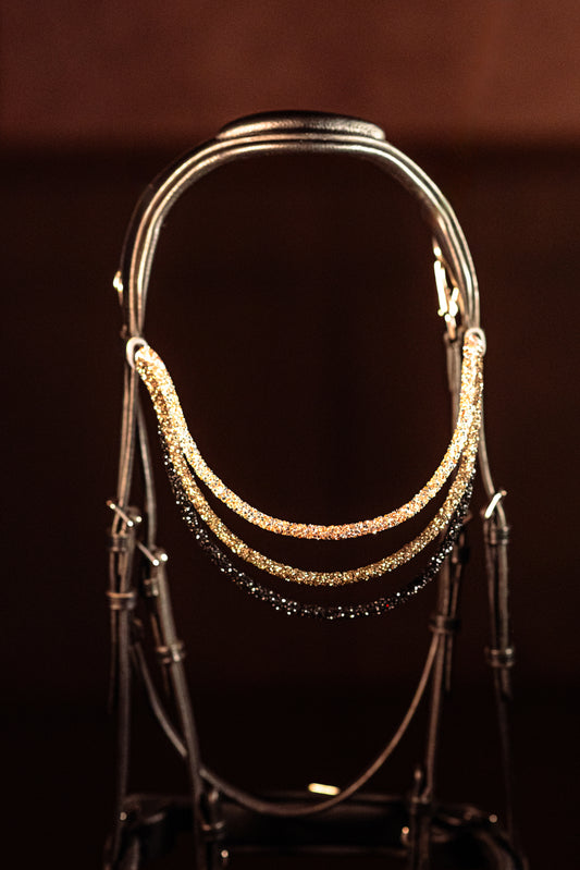 This browband Spectrum Tripple Topaz Ombre
Experience a new dimension of browband design. Crafted with three soft, flexible tubes, each generously sprinkled with dazzling rhinestones, this piece offers a unique texture and radiant sparkle. An internal metal wire allows for effortless shaping, ensuring a perfect contour to your horse's brow and maintaining its elegant form.
Each browband is handmade from scratch using premium European materials and durable leather. Featuring our exclusive magnetic snap