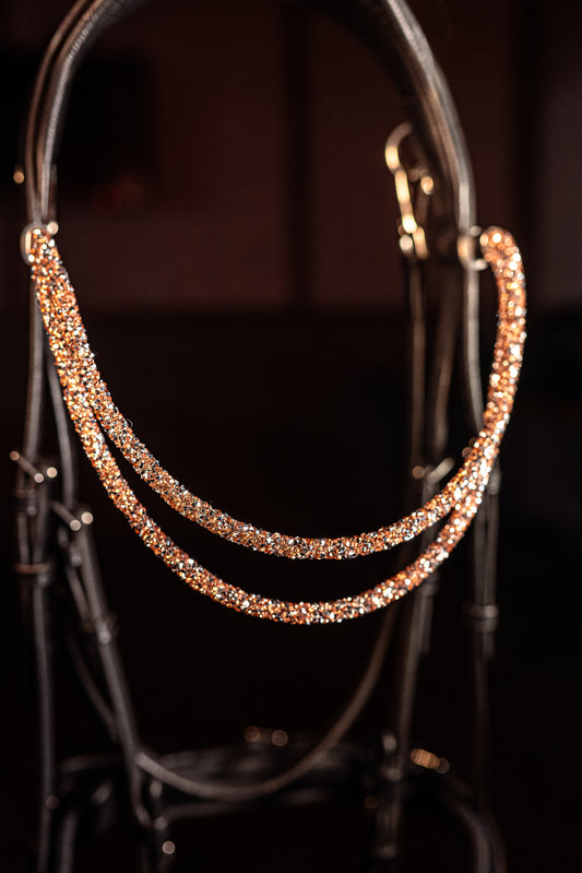 Experience a new dimension of browband design. Crafted with three soft, flexible tubes, each generously sprinkled with dazzling rhinestones, this piece offers a unique texture and radiant sparkle. An internal metal wire allows for effortless shaping, ensuring a perfect contour to your horse's brow and maintaining its elegant form.
Each browband is handmade from scratch using premium European materials and&nbsp;durable leather. Featuring our exclusive magnetic snap