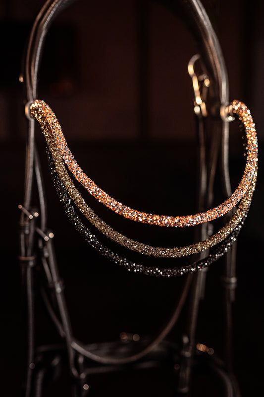 This browband Spectrum Tripple Topaz Ombre
Experience a new dimension of browband design. Crafted with three soft, flexible tubes, each generously sprinkled with dazzling rhinestones, this piece offers a unique texture and radiant sparkle. An internal metal wire allows for effortless shaping, ensuring a perfect contour to your horse's brow and maintaining its elegant form.
Each browband is handmade from scratch using premium European materials and&nbsp;durable leather. Featuring our exclusive magnetic snap